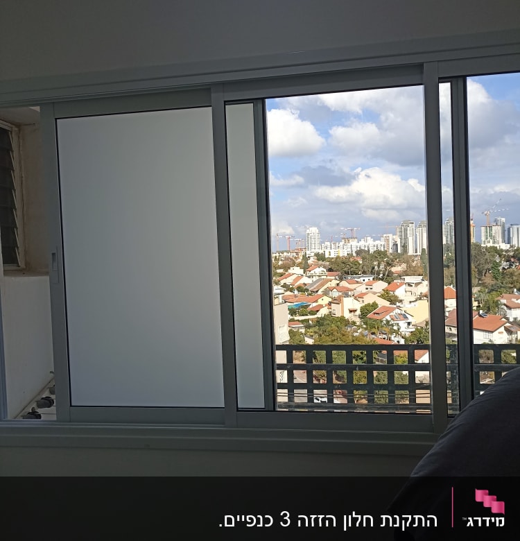 חלון אלומיניום עם זכוכית חלבית ונוף עירוני